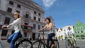 Eine Gruppe von Fahrradfahrer*innen vor dem beeindruckenden Rathaus in Güstrow genießt die historische Kulisse der Stadt.