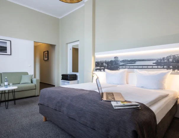 Helles Komfortzimmer mit Doppelbett, Sessel und eleganter Einrichtung im Hotel am Schlosspark