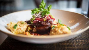 Ein Teller mit geschmorter Ochsenbacke, serviert mit saisonalen Beilagen, angerichtet im Restaurant Wallenstein in Güstrow.
