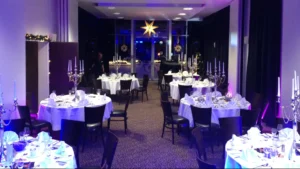 Runde 8er-Tische mit eleganter Dekoration und Lichtinszenierung schaffen eine festliche Atmosphäre für besondere Anlässe.