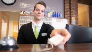 Ein Rezeptionist übergibt dem Gast nach der Bezahlung die Zimmerkarte während des Check-ins im Hotel am Schlosspark Güstrow.
