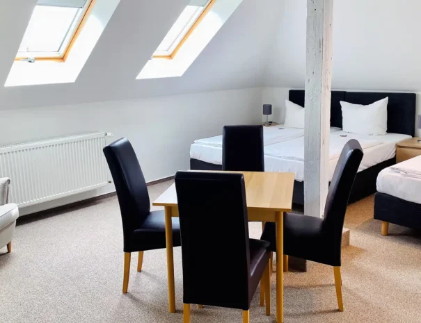 Gemütliches Dachgeschoss-Familienzimmer mit Einzelbetten, Sessel und Esstisch im Hotel am Schlosspark