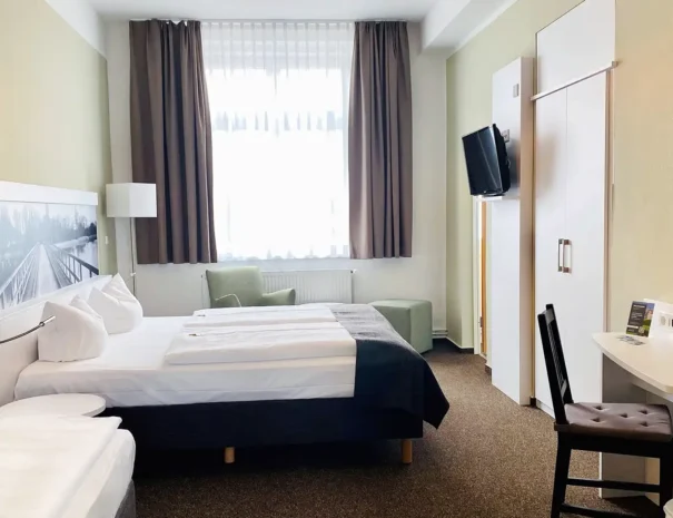 Familienzimmer mit komfortablem Doppelbett und getrenntem Einzelbett, ideal für Familienaufenthalte im Hotel am Schlosspark.