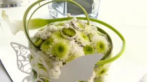 Zwei goldene Trauringe liegen auf einem liebevoll arrangierten Blumenbouquet als ein Symbol für Liebe und Verbundenheit.