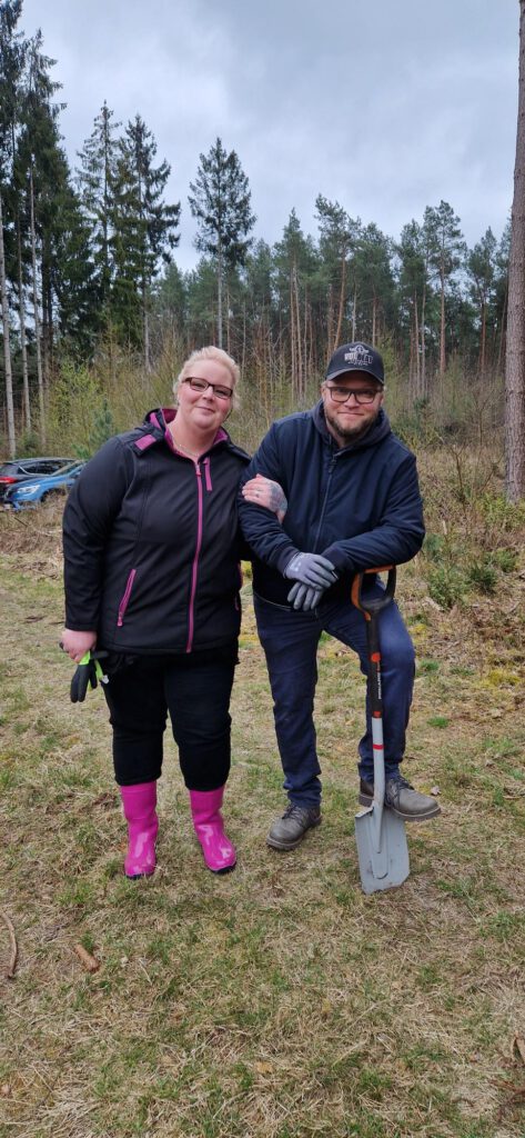 2 Mitarbeiter des Hotels im Wald mit Sparten um Bäume zu pflanzen