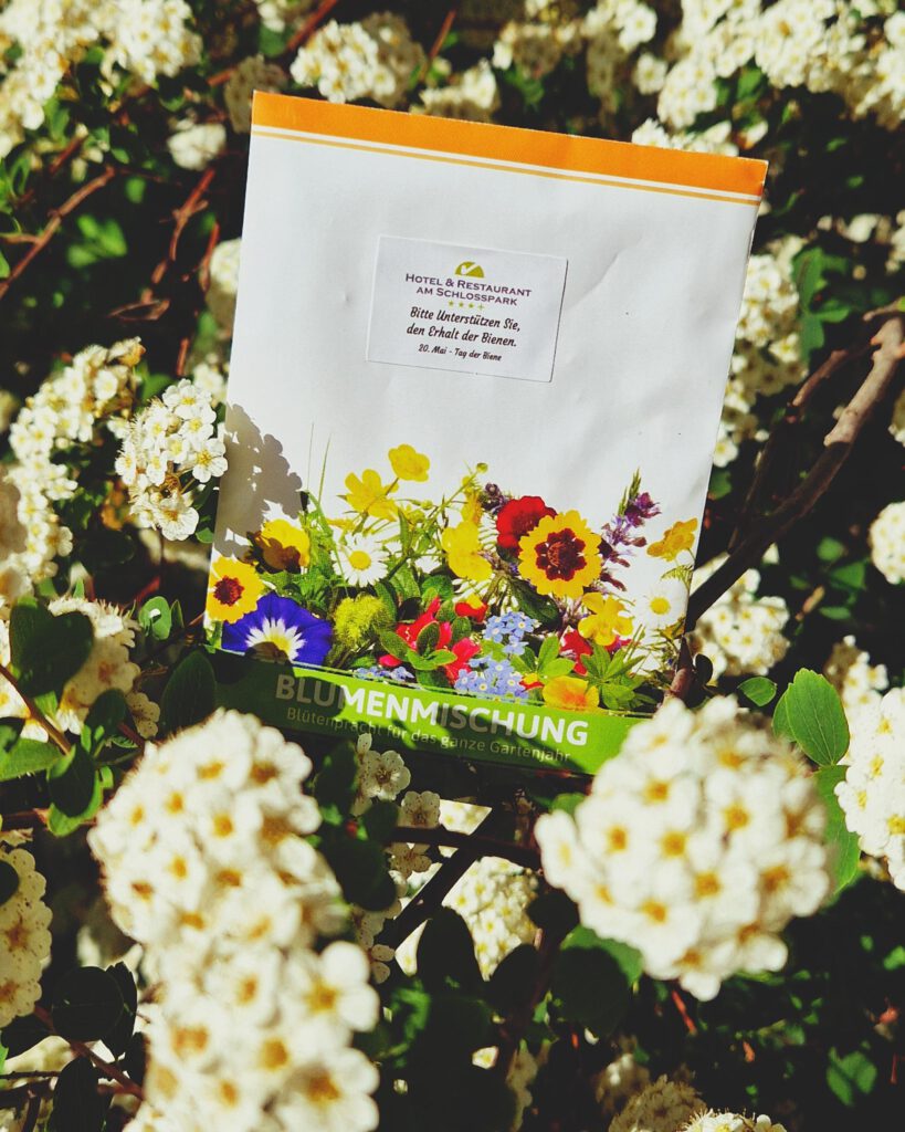 Blumenblüten in denen eine Tüte mit Blumensamen stehet